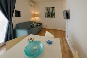 Ein Wohnzimmer mit einer Couch, einem Tisch mit Dekoration, einer Lampe und einem Bild an der Wand.