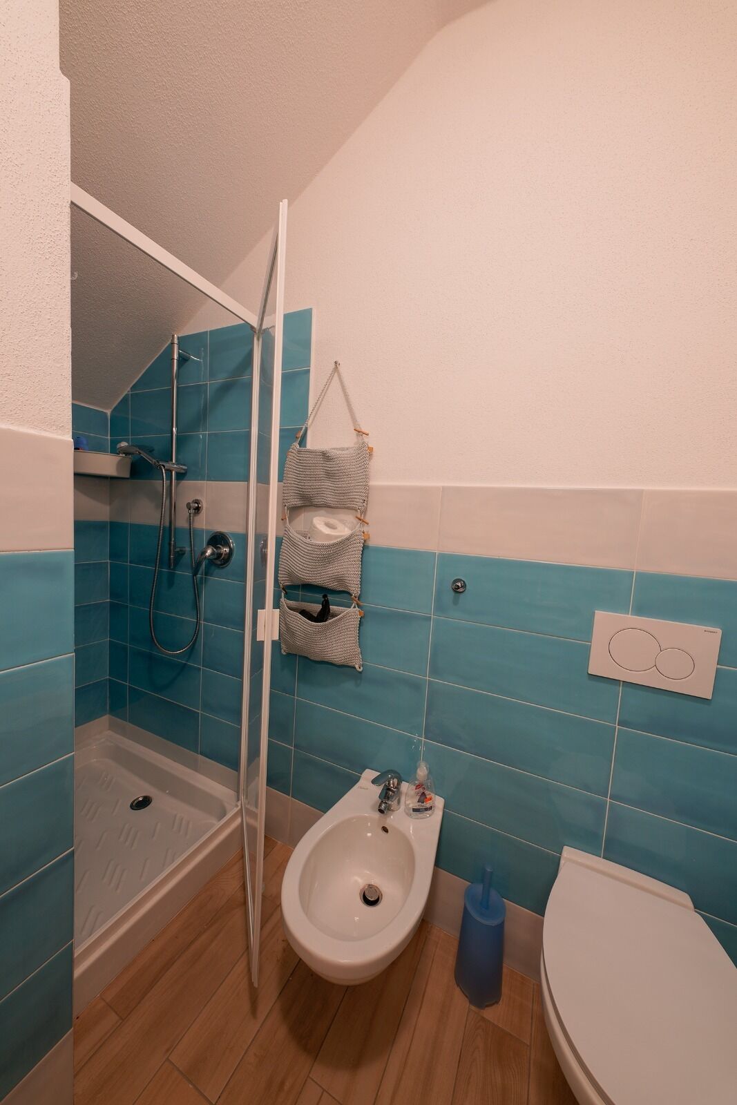 A bathroom with a shower, bidet, toilet, and a towel rack.