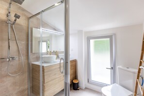 Un baño moderno con cabina de ducha de vidrio, lavabo blanco y retrete.