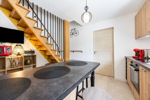 Eine moderne Küche mit einer Holztreppe, einem Essbereich mit einem langen Tisch und einem an der Wand befestigten Fahrrad.