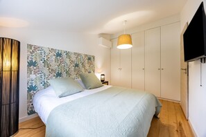Un dormitorio con cama, mesita de noche, lámpara, televisor y armario.
