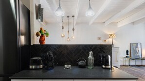 Una cucina moderna con piano di lavoro nero, cassetti bianchi, lampade a sospensione e un vaso decorativo.