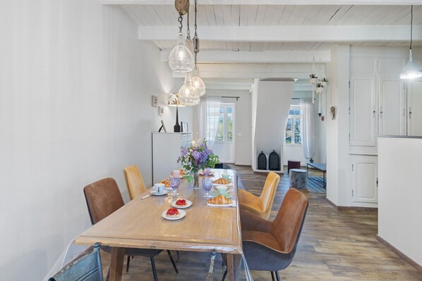 A dining area with a wooden table, chairs, and a hanging light fixture.