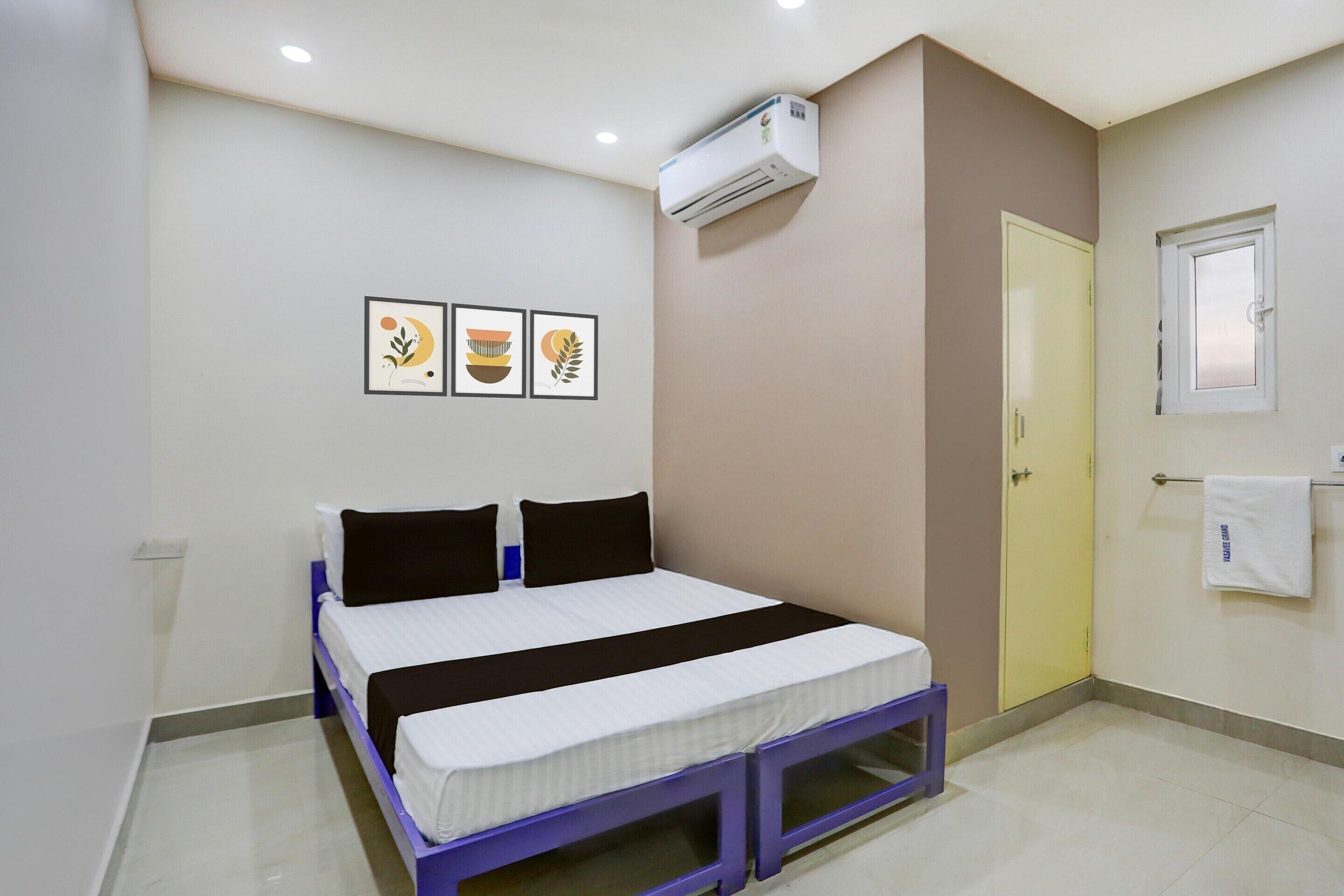 Un dormitorio con cama, unidad de aire acondicionado, puerta y toallero en la pared.