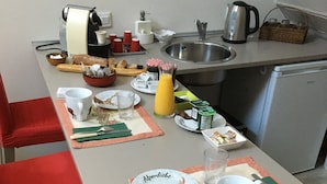 A dining table set with plates, cutlery, a glass of juice, and a kettle.