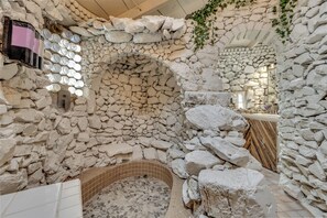A stone-walled bathroom with a built-in bathtub, a sink, and a shower area. - Tucson Bottle House - Both Main and Guest Houses - New Listing Discounts! (Tucson)