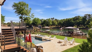 A pool area with lounge chairs, a hot tub, and a dock with boats. - Ultimate LKN Waterfront Home - Swim Up Bar Pool, Covered Deck, & Putting Green (Huntersville)