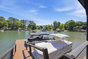 A dock with a boat, a clear view of the lake, and surrounding greenery. - Ultimate LKN Waterfront Home - Swim Up Bar Pool, Covered Deck, & Putting Green (Huntersville)