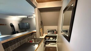 Una cocina compacta con horno empotrado, un lavamanos y una pequeña encimera.