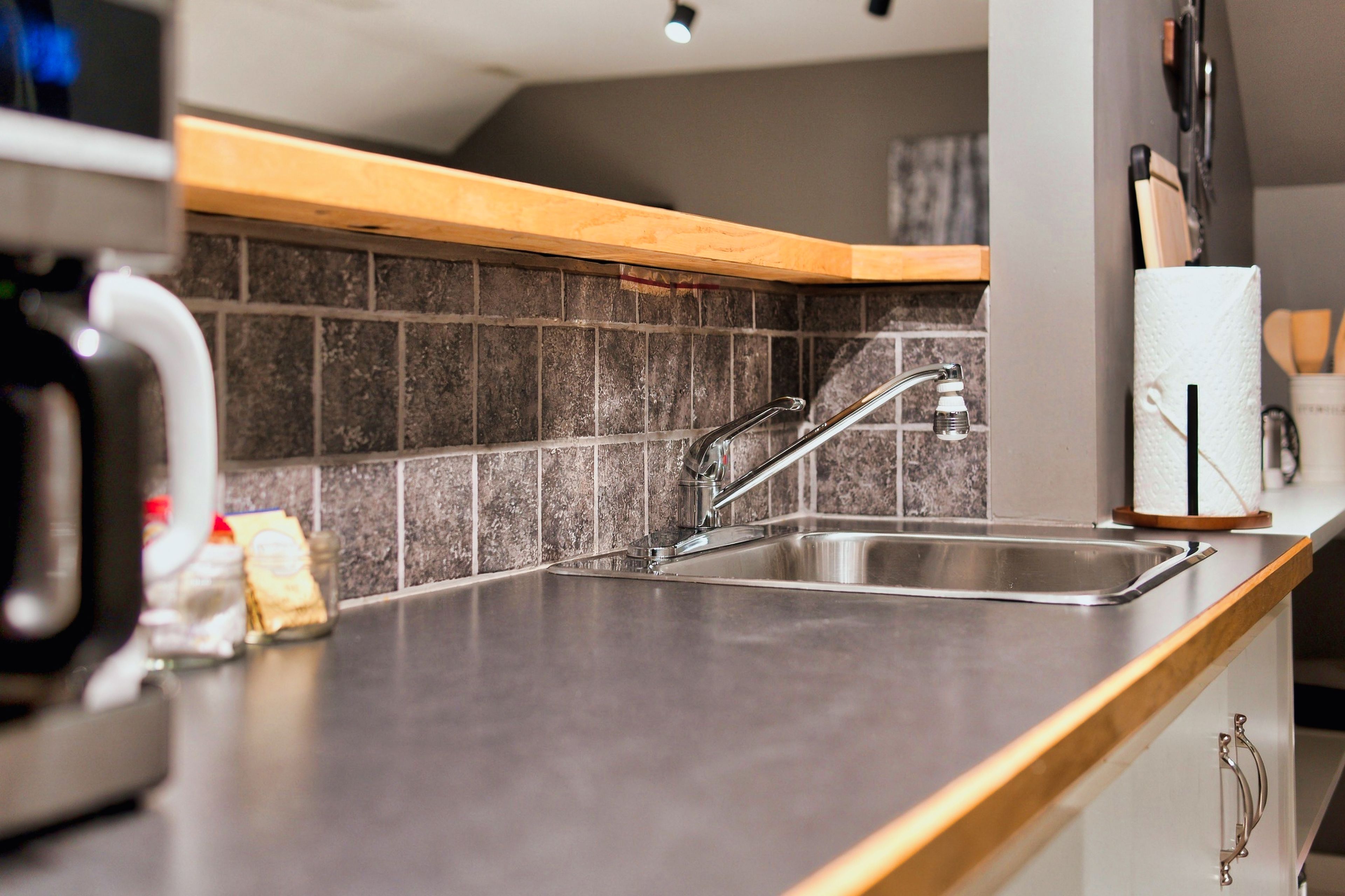 Een moderne keuken met een roestvrijstalen spoelbak, een houten aanrechtblad en een betegelde achterwand.