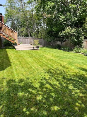 Un jardin avec une terrasse en bois, un petit espace patio et une clôture en bois.