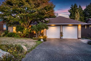 A residential house with a garage, driveway, and landscaped garden.