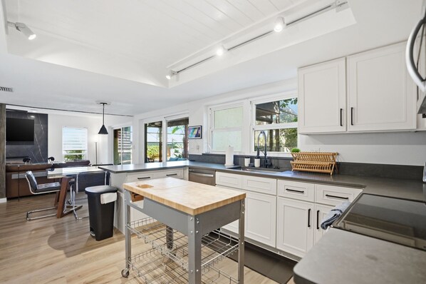A modern kitchen with white cabinets, a wooden countertop, and a built-in oven. - Tampa Oasis: Pool & Hot Tub Retreat for Families (Tampa)