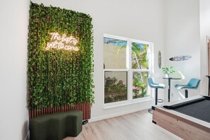 A modern room with a green vertical garden wall, a neon sign, a pool table, and two blue chairs. - Tampa Oasis: Pool & Hot Tub Retreat for Families (Tampa)