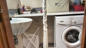 Eine Küche mit Waschmaschine, Wäscheständer und einer Kleiderstange.