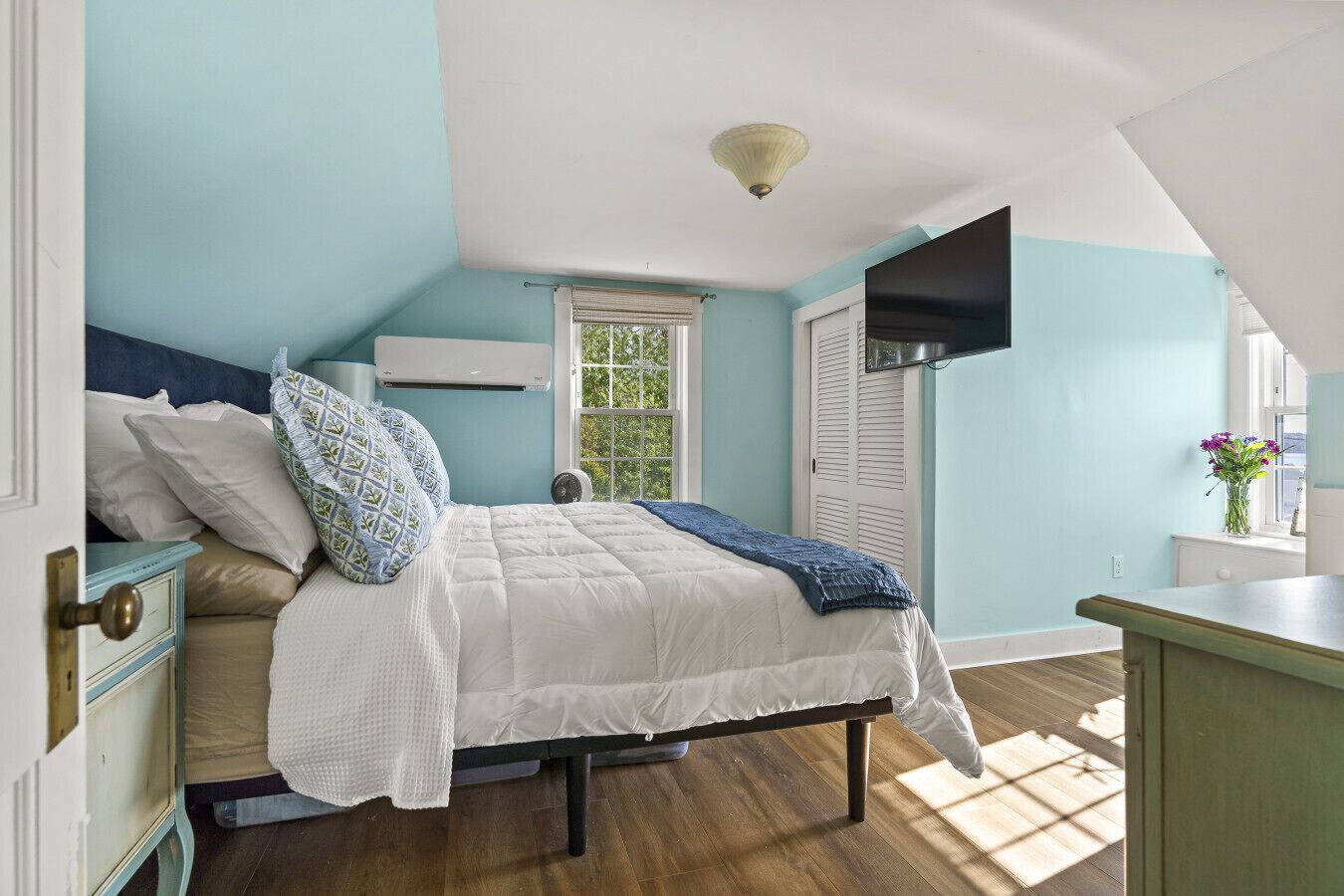 A bedroom with a bed, a window, a dresser, and a ceiling fan.