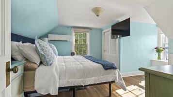 A bedroom with a bed, a window, a dresser, and a ceiling fan.
