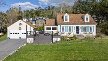 A residential property with a garage, a covered patio, and a front yard with a wooden deck.