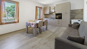 A modern kitchen with a dining area, a sofa, and a washing machine. - Apartment with 3 Beds (Mira)