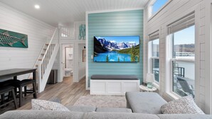 Ein modernes Wohnzimmer mit großem Flachbildfernseher, einer Treppe und Seeblick.