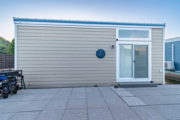 Un edificio con fachada gris, una puerta azul y un cartel en la pared.