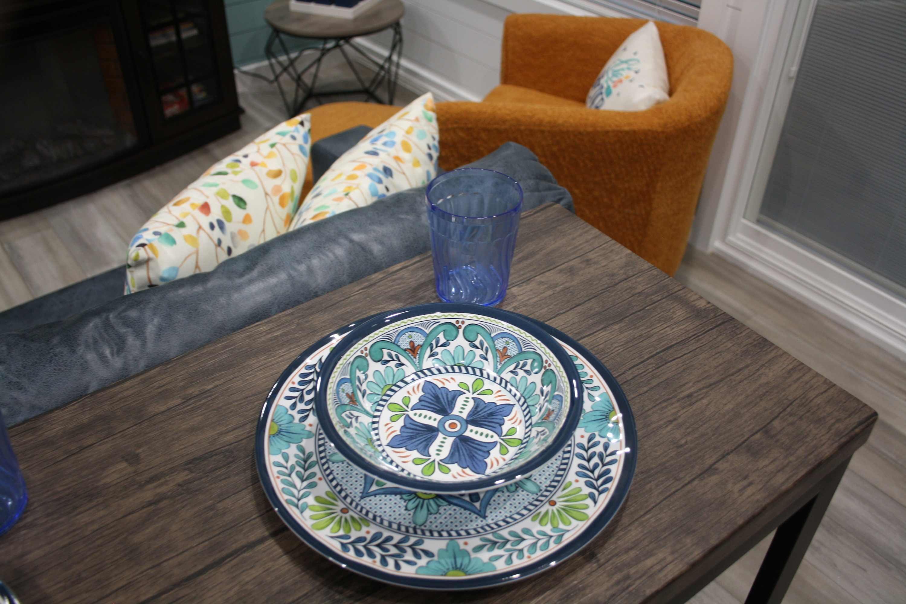 A dining table with a blue glass and a decorative plate set.