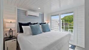 Une chambre à coucher avec un lit, une table de chevet, une lampe et une vue sur un balcon.