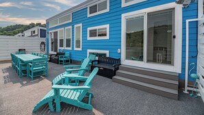 A blue mobile home with a patio area featuring outdoor furniture. - Four Suns - Lake Front Floating House Retreat (Russell Springs)