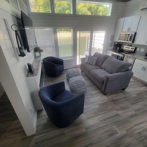Une cuisine moderne avec des meubles blancs, un canapé gris et un fauteuil bleu.