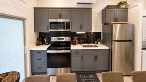 A modern kitchen with grey cabinets, stainless steel appliances, and a 'lake life is the best life' placard on the table. - Pet-Friendly Floating House on the Lake (Russell Springs)