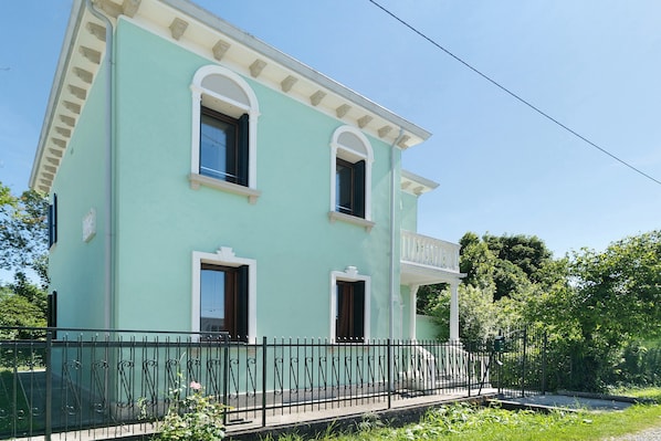 Un bâtiment à deux étages doté d’un balcon, d’un petit porche et d’une clôture en métal noir.