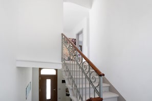 Un escalier avec une main courante en bois et des balustres en métal, menant à l’étage supérieur.