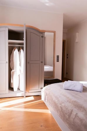 A bedroom with a bed, a wardrobe, and a mirror.