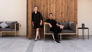 A modern outdoor seating area with a wooden backdrop, a grey sofa, and a small table with a plant. - Das Weinkitz  (Kitzeck im Sausal)