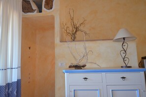 A room with a blue and white dresser, a lamp, and a wall-mounted vase with branches. - Ftam-corn01 in Tamarispa (Budoni)