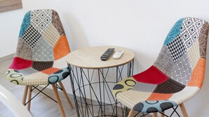 Twee stoelen met kleurrijke stoffen bekleding en een kleine ronde tafel met een afstandsbediening erop.