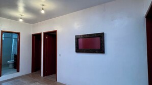 A hallway with a patterned floor, a wall-mounted mirror, and two doors.