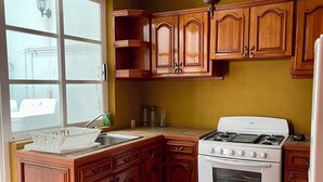 A kitchen with wooden cabinets, a stove, and a window.