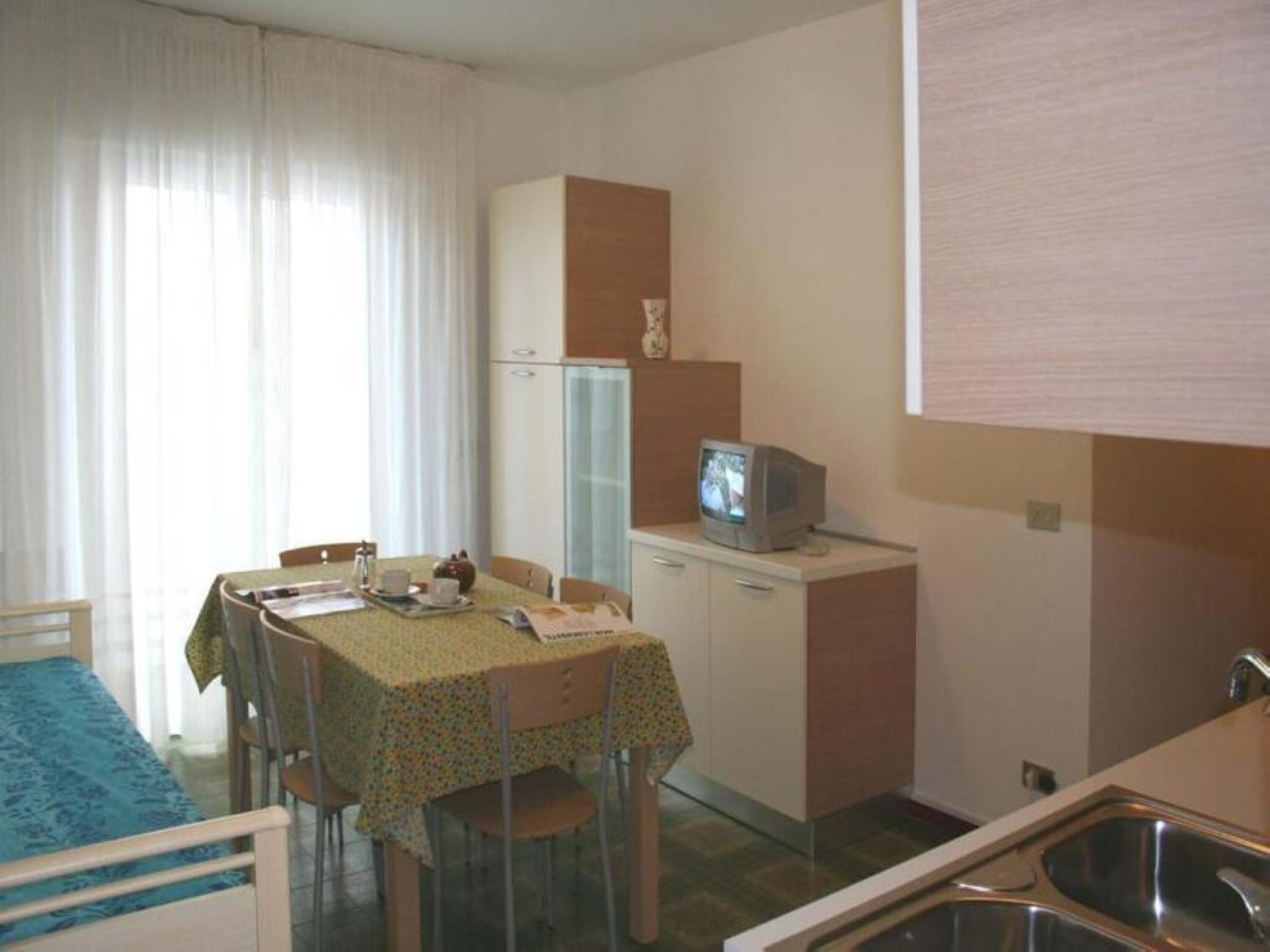 A compact hotel room with a dining area, a kitchenette, and a television.