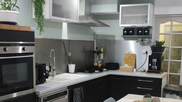 Uma cozinha compacta com forno embutido, máquina de café e pia.