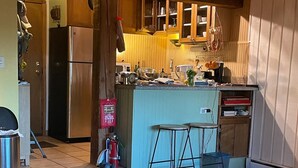 Une cuisine moderne avec des meubles en bois, un réfrigérateur en acier inoxydable, un évier et un coin bar.