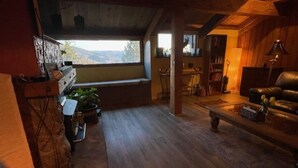 Une pièce chaleureuse avec un plancher en bois, un banc, un canapé et une bibliothèque.