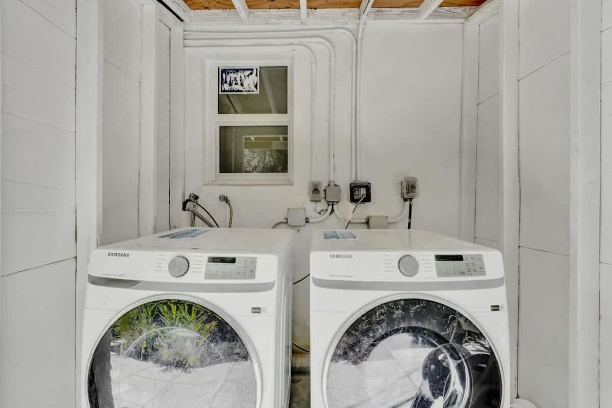 Lavandería con dos lavadoras Samsung, una ventana y enchufes eléctricos.