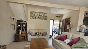 A living room with a sofa, a coffee table, a bookshelf, and a painting on the wall. - Detached, newly refurbished, 3 bed house with parking, 2 min walk from the beach (Fuengirola)