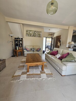 A living room with a sofa, a coffee table, a bookshelf, and a painting on the wall. - Detached, newly refurbished, 3 bed house with parking, 2 min walk from the beach (Fuengirola)