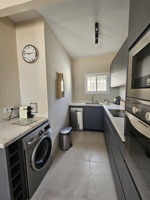 A compact kitchen with a washing machine, dishwasher, and a built-in oven. - Detached, newly refurbished, 3 bed house with parking, 2 min walk from the beach (Fuengirola)