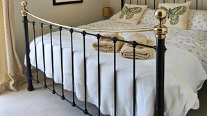 A bed with a black metal frame, white bedding, and decorative pillows. - Detached, newly refurbished, 3 bed house with parking, 2 min walk from the beach (Fuengirola)