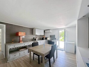 Une cuisine moderne avec un coin repas, des appareils électroménagers intégrés et une vue sur l’extérieur.
