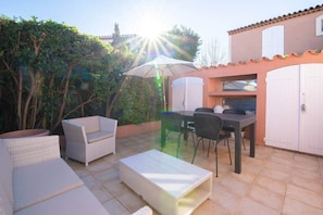 An outdoor patio with wicker furniture, a table, and a grill area. - Charming Provençal farmhouse, residence with swimming pool (Gassin)
