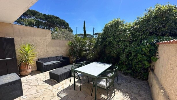 Um pátio externo com piso de pedra, uma mesa, cadeiras e um conjunto de sofás.